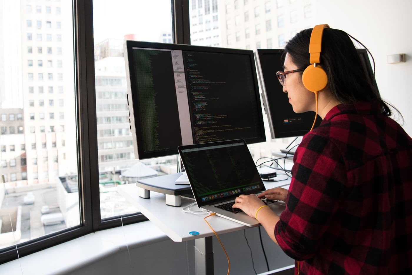 A developer coding a website at a standing desk in a bright, modern workspace