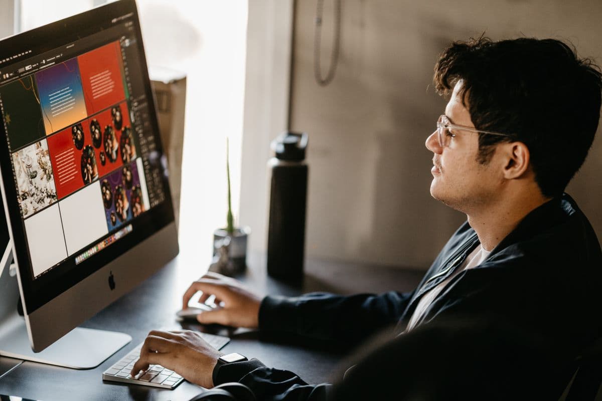 A graphic designer working on colorful brand layouts on a computer