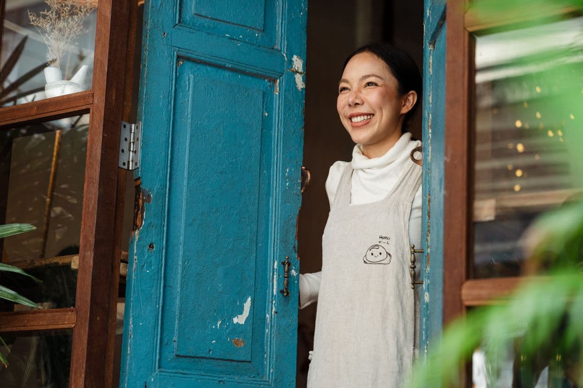 A local small business owner smiling at the entrance of her shop