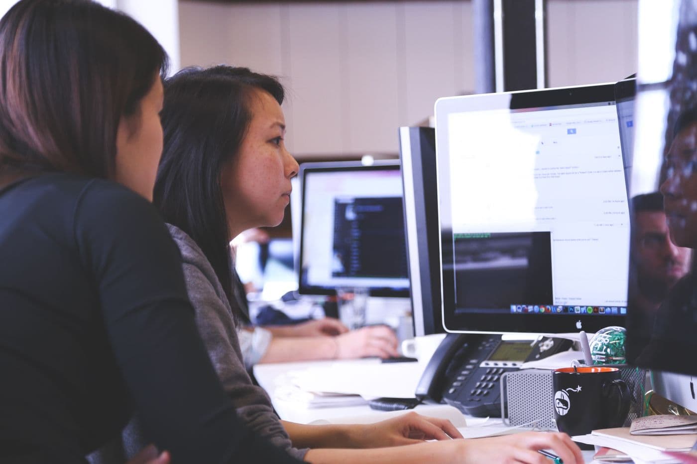 Two web specialists reviewing and optimizing a website on desktop monitors